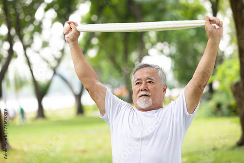 asian senior man workout and stretching with white towel in the park