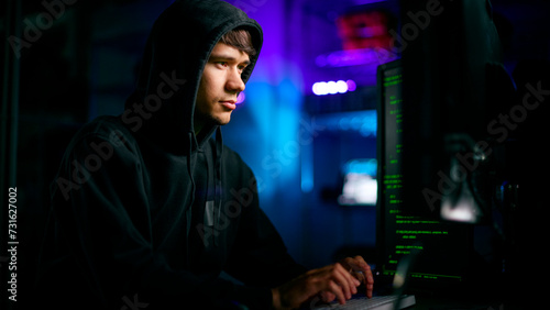 Low Key Lighting Shot Of Male Computer Hacker Sitting In Front Of Screens Breaching Cyber Security