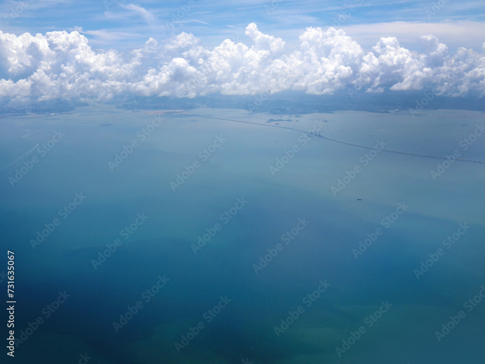 Aerial shot of sea water in turquoise color with cloudscape in the sky, many ships or cruise onboard below, tranquil sky scene, earth from above