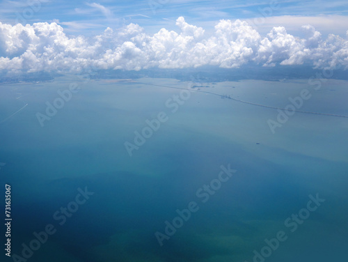 Aerial shot of sea water in turquoise color with cloudscape in the sky  many ships or cruise onboard below  tranquil sky scene  earth from above