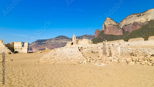 Ruinas del pueblo de Sant Roma de Sau, con su icónico campanario, resurgen del embalse de Sau, bajo los escarpados riscos de la comarca de Osona en Cataluña.