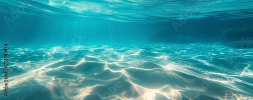 Clear blue ocean water above a sandy sea floor with natural light creating mesmerizing ripples underwater