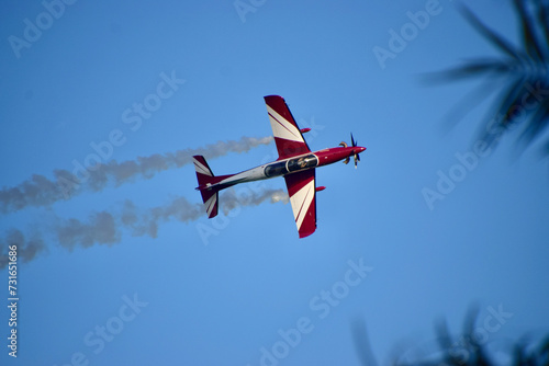 pilot clearly visible in an airshow of aerobatic planes showcasing parachutes paramotor skydiving show with colors
