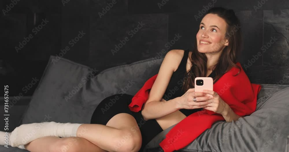 Focused millennial woman using mobile phone at home, reading online content, browsing internet, shopping with application. Girl texting message on chat on cellphone at home, thinking about answear. Focused millennial woman using mobile phone at home, reading online content, browsing internet, shopping with application. Girl texting message on chat on cellphone at home, thinking about answear.