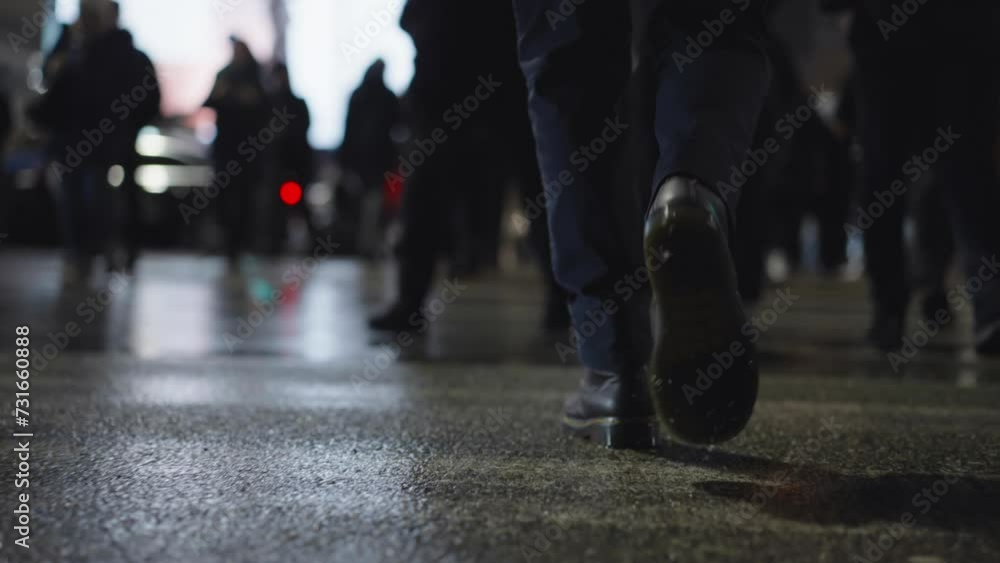 Rear back view male feet steps crossing busy street at night. Man wearing dark leather boots goes on pedestrian crossing in city. Low angle people crowd legs walking sidewalk, rainy autumn weather Rear back view male feet steps crossing busy street at night. Man wearing dark leather boots goes on pedestrian crossing in city. Low angle people crowd legs walking sidewalk, rainy autumn weather