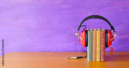 Relaxing with audiobooks concept with heap of books and vintage earphones.Background with large copy space, panoramic.
