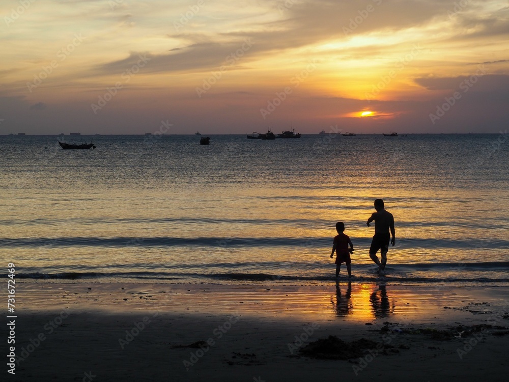 Panoramic sunset on the beach with silhouettes of a father and a child, fiery sky background