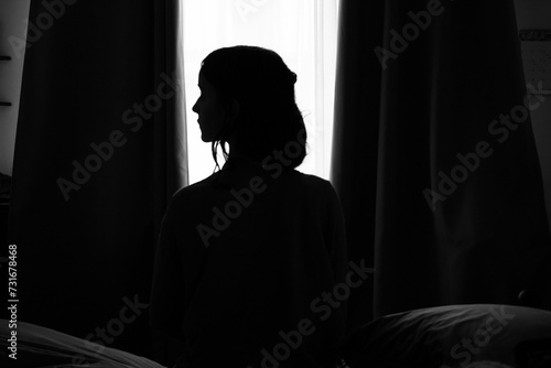 Silhouette of female sitting on bed dark room