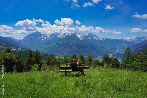 Adult couple embracing on a bench while looking at the beautiful rocky mountains