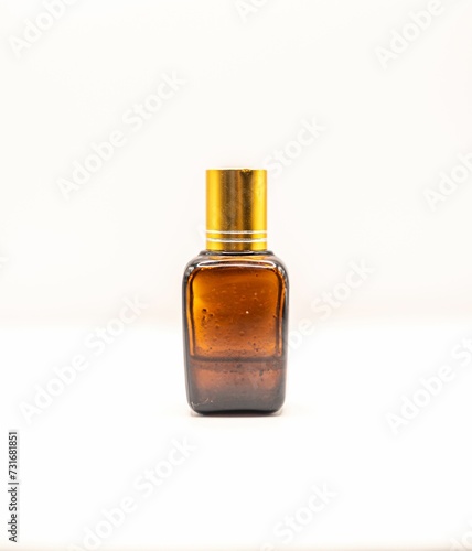 Closeup of a brown bottle of female perfume with a golden cap isolated on a white background