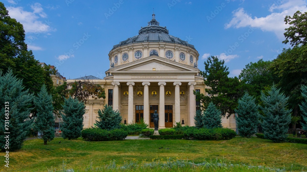 Romanian Athenaeum in Bucharest tall trees and bright green shrubs in the garden