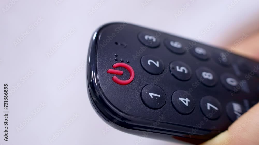Female hand with TV remote pressing power switch on and off button close up Female hand with TV remote pressing power switch on and off button close up