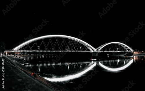 Illuminated Zezelj bridge spanning a night-time river with light trails from passing vehicles
