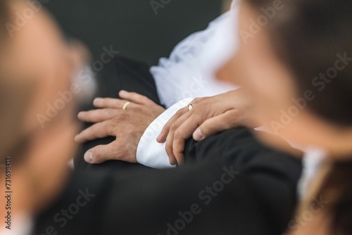 Closeup shot of a a newly married couple, both wearing their wedding rings, sitting together photo