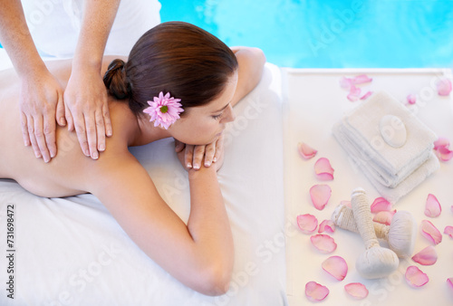 Flowers, massage and woman at spa pool for health, wellness and luxury holistic treatment. Self care, peace and girl on table with masseuse for body therapy, relax and calm hotel service with petals