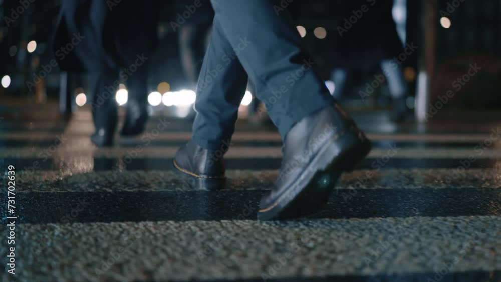 Rear back view male feet steps crossing busy street at night. Man wearing dark leather boots goes on pedestrian crossing in city. Low angle people crowd legs walking sidewalk, rainy autumn weather Rear back view male feet steps crossing busy street at night. Man wearing dark leather boots goes on pedestrian crossing in city. Low angle people crowd legs walking sidewalk, rainy autumn weather