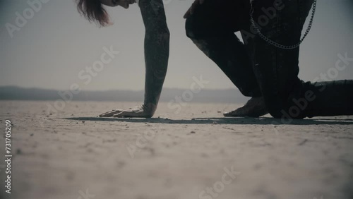 Never give up. Exhausted barefoot man walking through desert in pain and falls on his knee. Guy gets up and keep walking. Cinematic shot in slow motion. Dry lake. Cold color correction, 4k photo