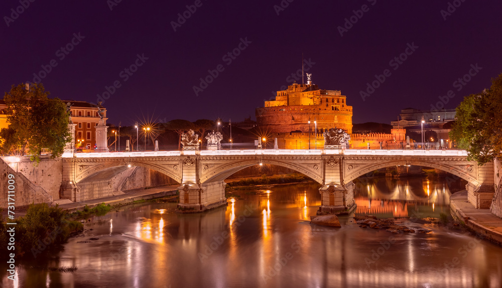 Bridge of the Holy Angel in Rome at night illuminated at sunset.