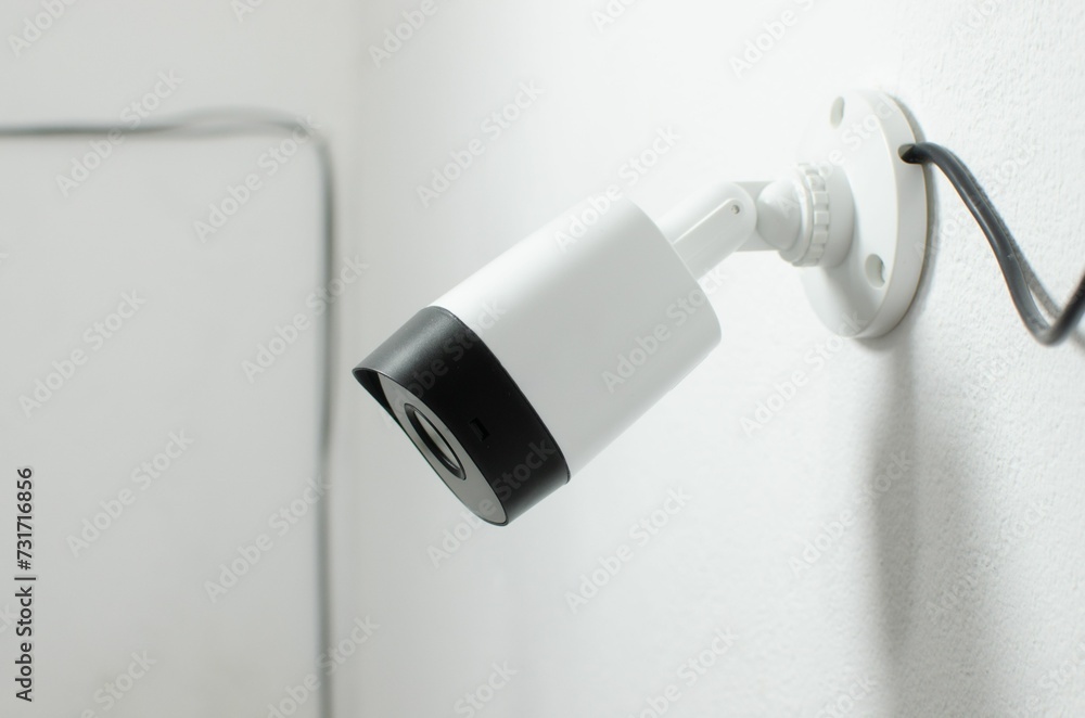 Close-up of a security camera mounted on a wall in a modern office, ready to be used