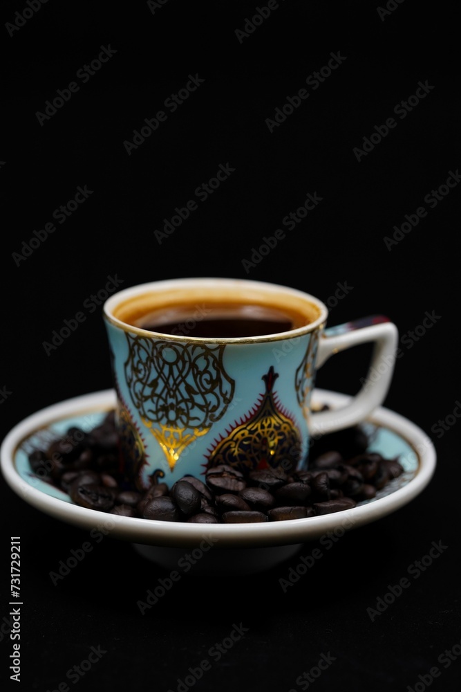 Obraz premium Close-up of black coffee in a blue cup with intricate golden designs on it