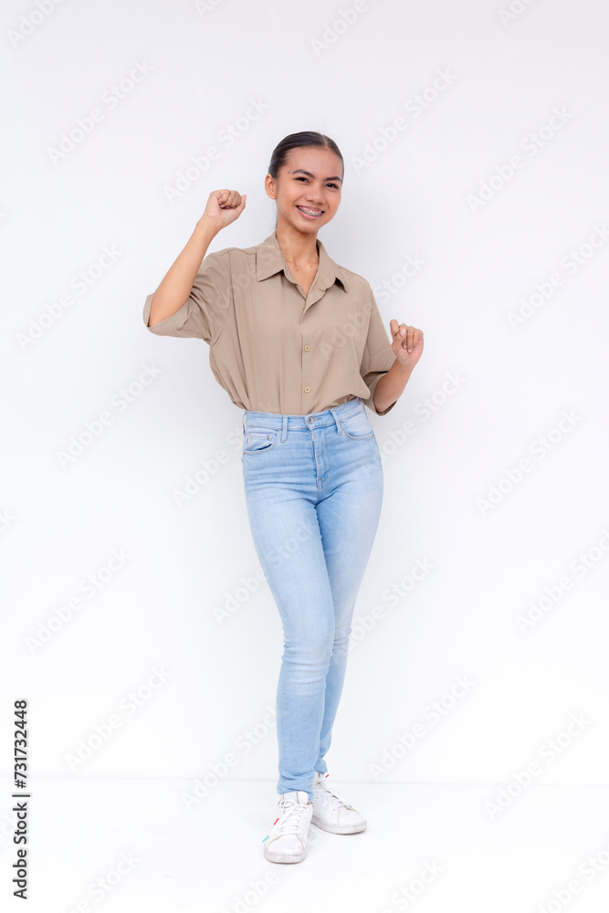 Young Filipino woman in casual clothing, smiling and celebrating with a little dance, isolated on a white background with copyspace. Young Filipino woman in casual clothing, smiling and celebrating with a little dance, isolated on a white background with copyspace.
