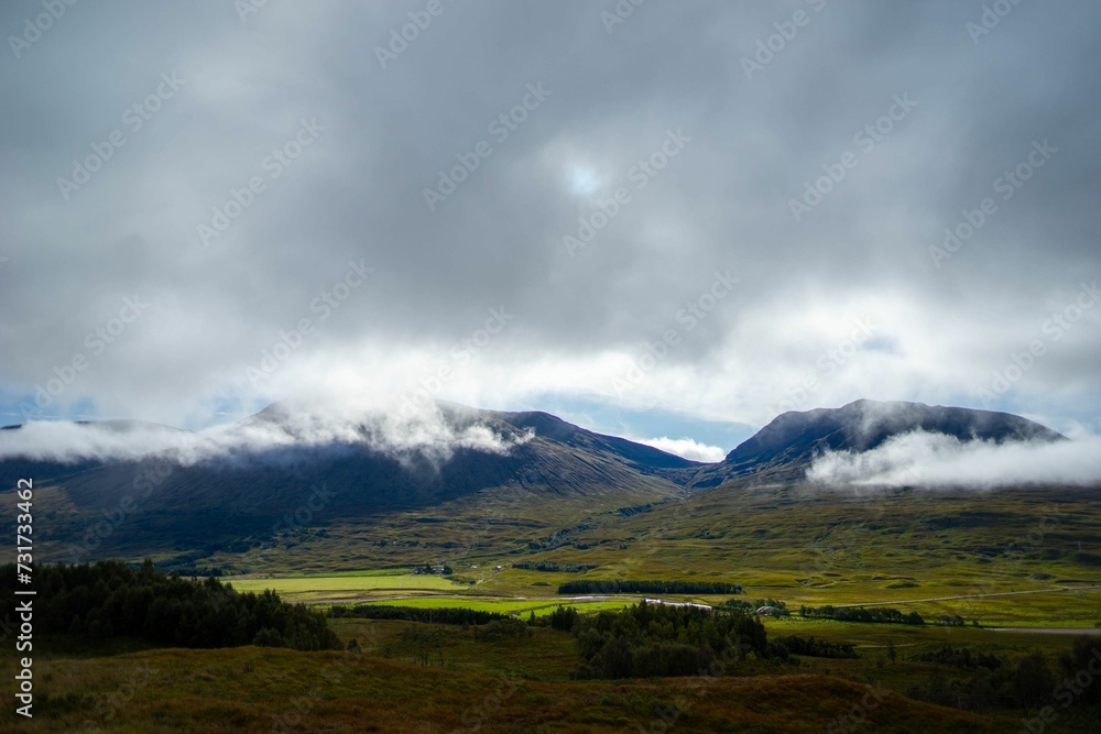 Stunning landscape of rolling green hills with majestic mountains in the background, Scotland