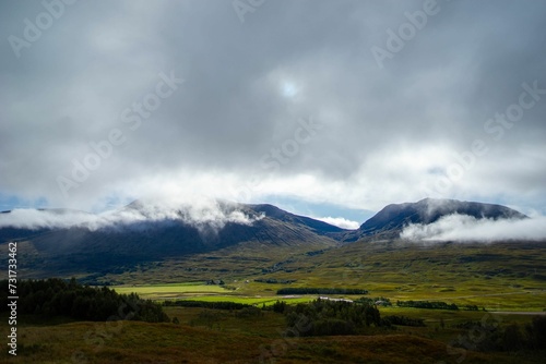 Stunning landscape of rolling green hills with majestic mountains in the background, Scotland