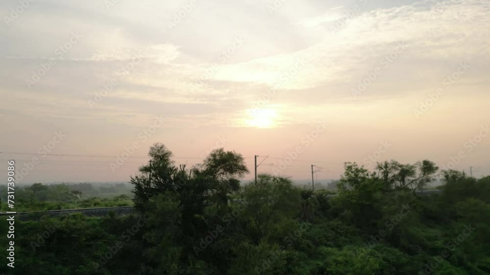 Aerial of the golden sunset shining over the green field and the road Aerial of the golden sunset shining over the green field and the road