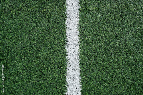 Texture of artificial grass with white line, green football field surface, close-up. Design element for website banners, social media posts, abstract sports background