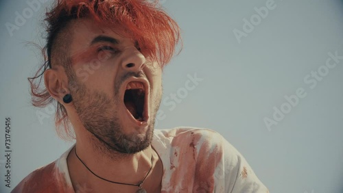 Badly wounded man screaming in pain. Loud screams. Vengeance and anger. Screaming in the desert. Loud shouts in the middle of nowhere. Bleeding mouth and bleeding person screaming. Warm color. photo