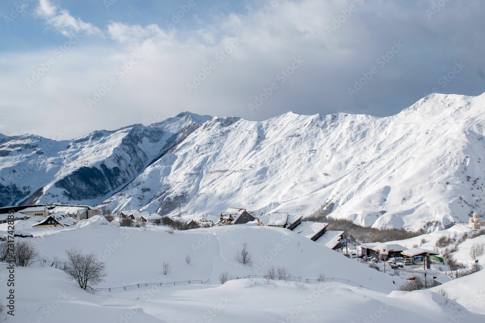 Scenic winter landscape featuring a snow-covered mountain range with a valley below