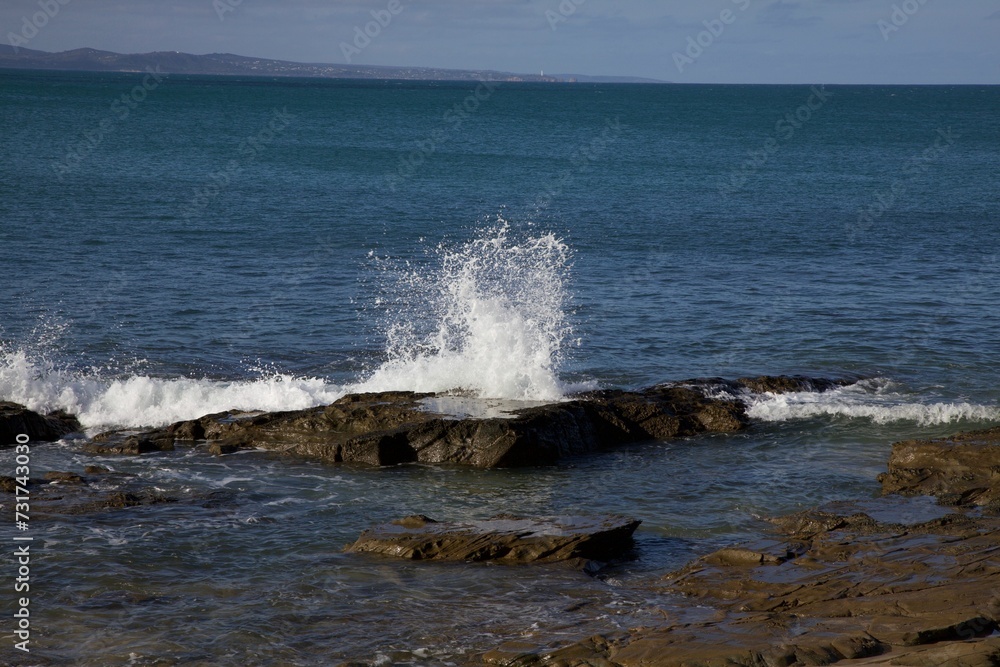 Powerful wave crashes against a rocky shoreline, creating an impressive splash of water