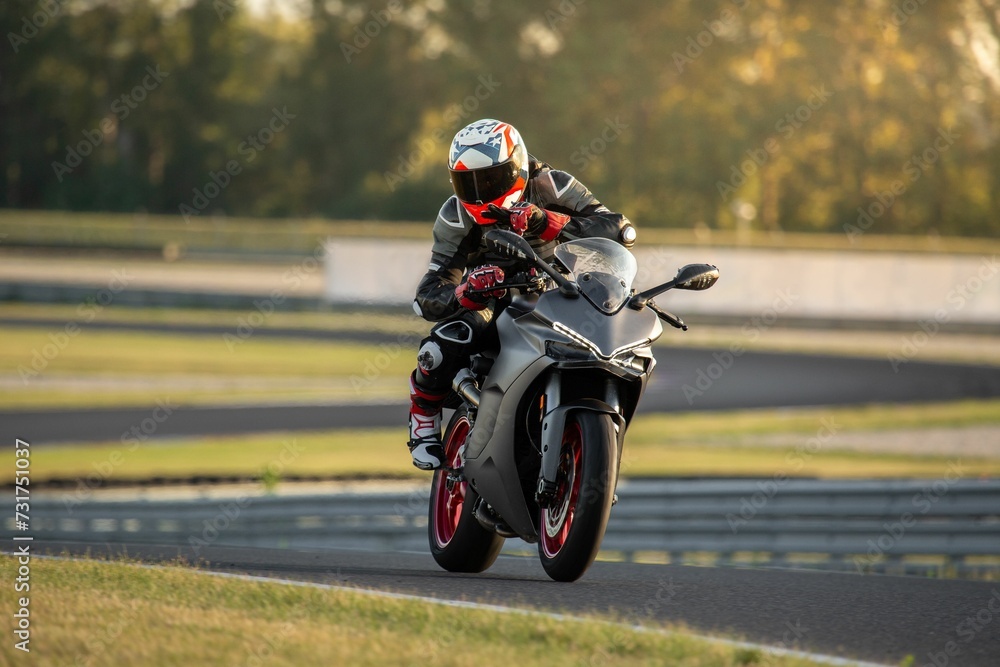 Motorcycle rider on a gray sport bike riding on the road at a race and looking at the camera