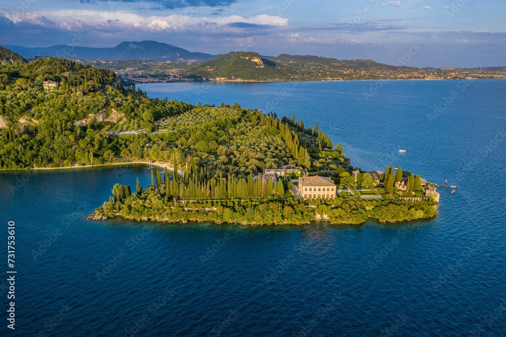 an island on a lake surrounded by trees and mountains in the background