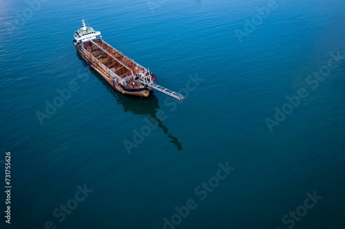 Idyllic scene of a boat leisurely drifting across a tranquil blue ocean © Wirestock
