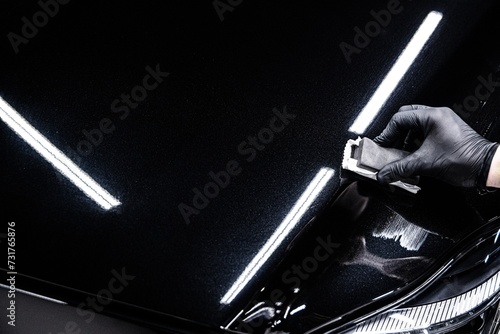 Car detailing worked carefully aplying ceramic coating on car hood. Copyspace photo