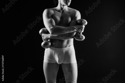 Fotografija Shirtless bodybuilder holding dumbell and showing his muscular arms
