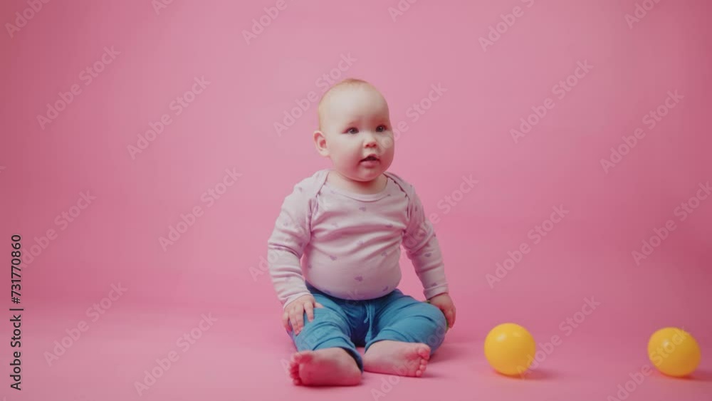 Cute little baby girl playing with colorful toy balls on pink background Cute little baby girl playing with colorful toy balls on pink background