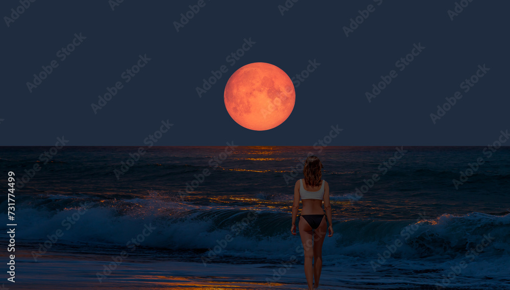 Night sky with moon in the clouds on the foreground power sea wave - Happy slim girl in red and black bikini  with raised up arms on the seashore in Alanya "Elements of this image furnished by NASA - obrazy, fototapety, plakaty 