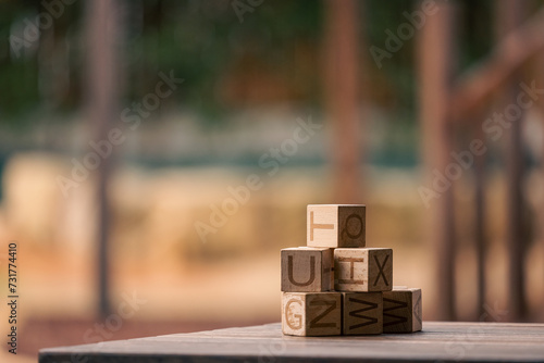 Stack of wooden building blocks with letters on blurred background with copy space