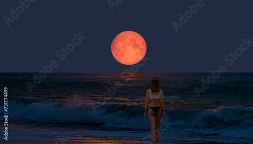 Night sky with moon in the clouds on the foreground power sea wave - Happy slim girl in red and black bikini  with raised up arms on the seashore in Alanya "Elements of this image furnished by NASA