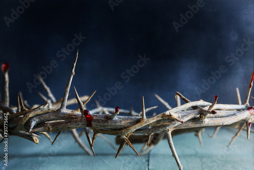 Dark moody Christian crown of thorns like Jesus Christ wore with blood drops over a rustic wood background or table. Selective focus with blurred background.
