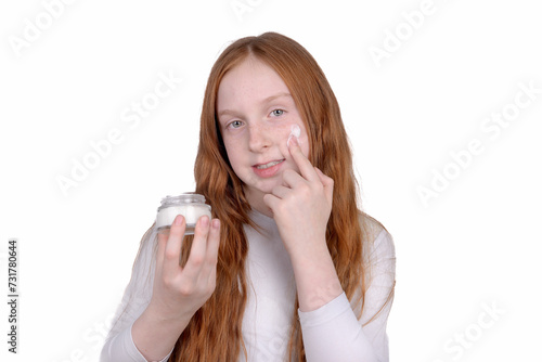 Redhead little girl with freckles uses face cream