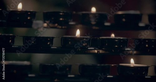 Candle light. Blurred candle light in a gothic church. Cathedrals praying candles. Candle of hope in gothic catholic church from medieval time. Short little candles. Many lines of candles. Cold colors