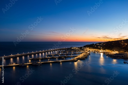 Scenic night view of a picturesque bay, illuminated by the surrounding city lights. © Wirestock