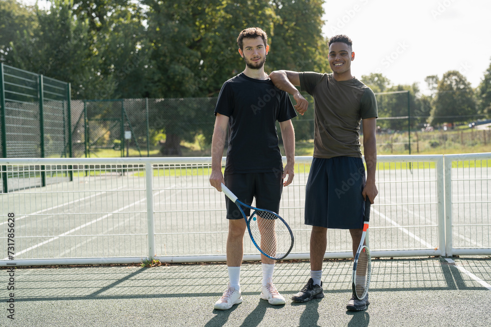Portrait of two men standing in tennis court