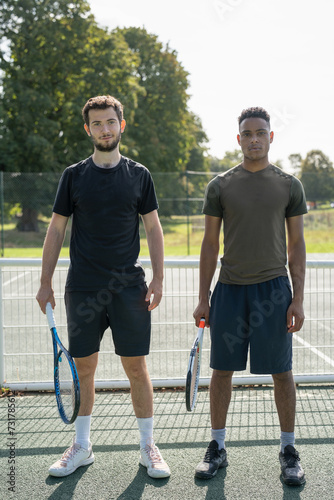 Portrait of two men standing in tennis court