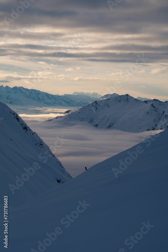 Vertical shot of mountains covered with white snow under the cloudy sky