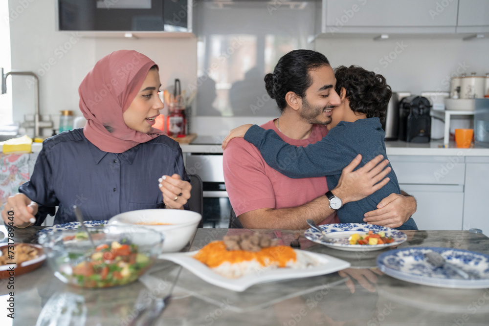 Boy (6-7) hugging father during family dinner