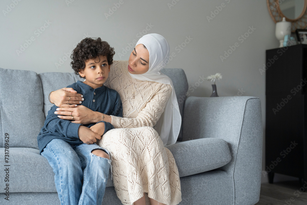 Mother hugging and comforting son (6-7) at home